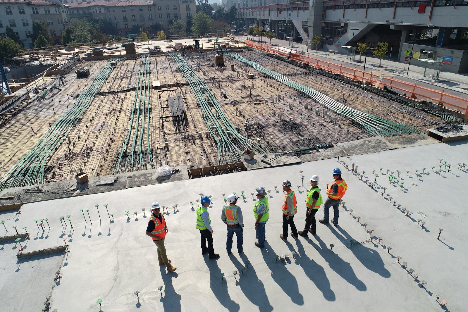 Bansal Group team on site — a freshly poured concrete slab, post-tension cables, and rebar.